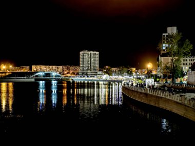 Sirk alanındaki Chelyabinsk şehrindeki Miass Nehri 'nin gece kıyısında suya, Rusya' ya ve Güney Urallar 'a çok renkli ışıklar yansıyor.
