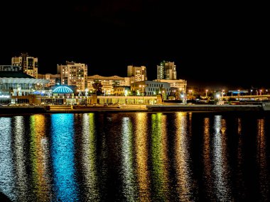 Sirk alanındaki Chelyabinsk şehrindeki Miass Nehri 'nin gece bankası suya, Rusya' ya, Güney Urallar 'a çok renkli ışıklar yansıyor.