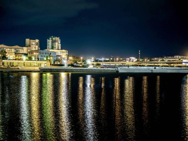 Sirk alanındaki Chelyabinsk şehrindeki Miass Nehri 'nin gece bankası suya, Rusya' ya, Güney Urallar 'a çok renkli ışıklar yansıyor.