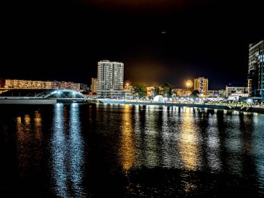 Sirk alanındaki Chelyabinsk şehrindeki Miass Nehri 'nin gece bankası suya, Rusya' ya, Güney Urallar 'a çok renkli ışıklar yansıyor.
