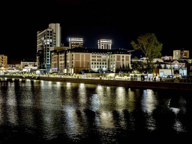 Sirk alanındaki Chelyabinsk şehrindeki Miass Nehri 'nin gece bankası suya, Rusya' ya, Güney Urallar 'a çok renkli ışıklar yansıyor.