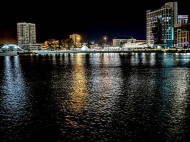 Sirk alanındaki Chelyabinsk şehrindeki Miass Nehri 'nin gece bankası suya, Rusya' ya, Güney Urallar 'a çok renkli ışıklar yansıyor.