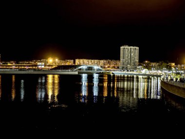 Sirk alanındaki Chelyabinsk şehrindeki Miass Nehri 'nin gece kıyısında suya, Rusya' ya ve Güney Urallar 'a çok renkli ışıklar yansıyor.