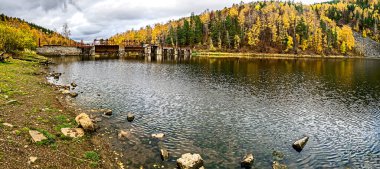 Sonbaharda Bolshaya Satka Nehri kıyısının panoramik manzarası solda Rusya 'da Porogy adı verilen ilk enerji santrallerinden birinin barajı bulunuyor.