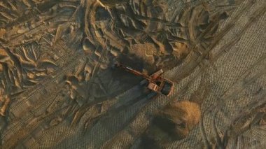 Kazı makinesi gün batımında inşaat alanında kum yüzeyi bile oluşturur.