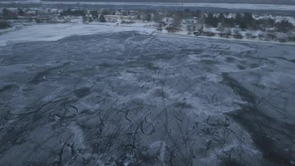Vuelo en avión no tripulado sobre un lago congelado donde los niños entrenan y juegan hockey cerca de la orilla en un día nublado — Vídeo de stock