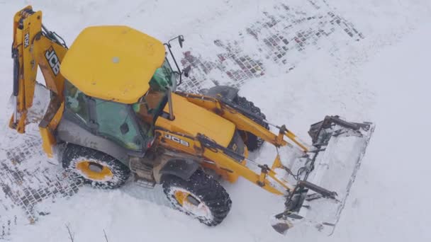 Gul traktor fjerner sne efter en snestorm, top view – Stock-video