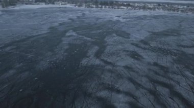 Bulutlu bir günde çocukların antrenman yaptığı ve kıyıya yakın hokey oynadığı donmuş bir gölün üzerinde İHA uçuşu.
