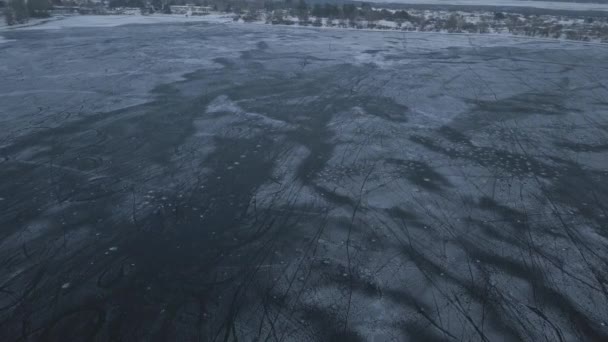Vuelo en avión no tripulado sobre un lago congelado donde los niños entrenan y juegan hockey cerca de la orilla en un día nublado — Vídeo de stock