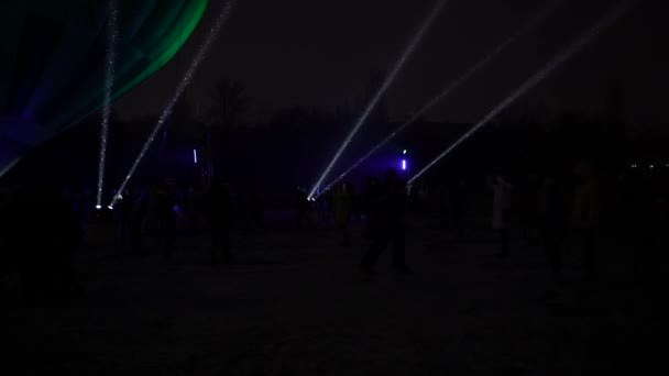 Projecteurs de concert la nuit lors d'une chute de neige, flocons de neige filant dans la lumière — Video