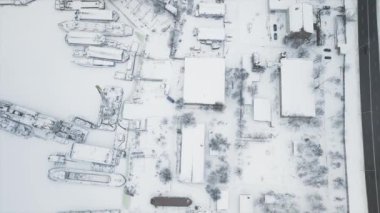 Karlı bir kış günü, gemilerin buz içinde donduğu tersanenin tam üstünde bir dron ile uçmak.