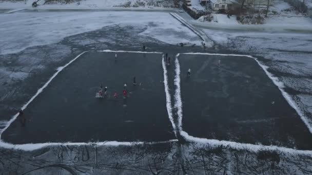 Vista panorâmica de um lago congelado no qual as crianças treinam jogando hóquei em um dia de inverno — Vídeo de Stock