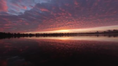 Colorful yellow-red dawn over the river with clouds and wind time-lapse
