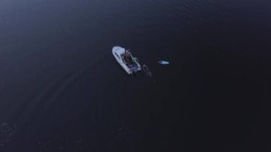 Tekne, suda yüzen sörfçüleri alır, akşam kuşları görür. Yüksek kalite 4k görüntü