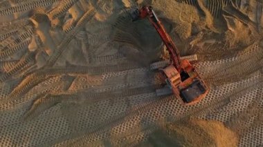 Excavator at work leveling the surface with sand at a construction site top view. High quality FullHD footage