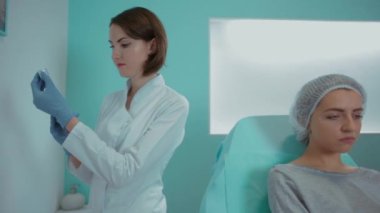 Ofisteki güzellik uzmanı müşterinin yüzünü yakın plan kalemle işaretliyor. Gülümseyen kız