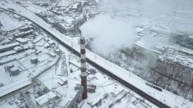 Gemileri ve buzda donmuş su muslukları olan bir yükleme rıhtımının olduğu bir sanayi bölgesinin üzerinden uçmak. Duman dumanları, şehrin arka planında üretilen buhar. Yüksek kaliteli FullHD görüntüler