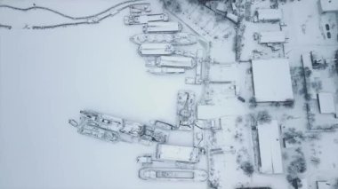 Karlı bir kış günü, gemilerin buz içinde donduğu tersanenin tam üstünde bir dron ile uçmak. Yüksek kaliteli FullHD görüntüler