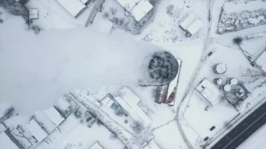 Gemileri ve buzda donmuş su muslukları olan bir yükleme rıhtımının olduğu bir sanayi bölgesinin üzerinden uçmak. Duman dumanları, şehrin arka planında üretilen buhar. Yüksek kaliteli FullHD görüntüler