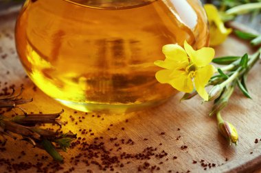 Arka planda bir şişe çuha çiçeği ve ön planda tohumlar olan Oenothera biennis çiçeği.