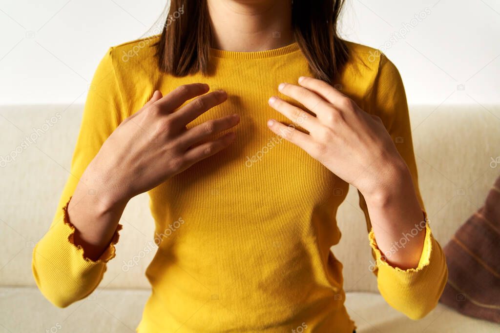 Teenage girl in yellow top practicing EFT or emotional freedom technique - tapping on collarbone point