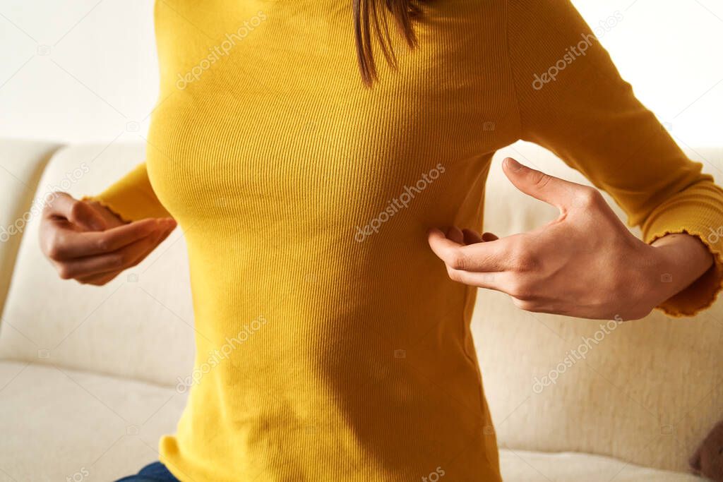 Teenage girl in yellow top practicing EFT or emotional freedom technique at home - tapping under the arm