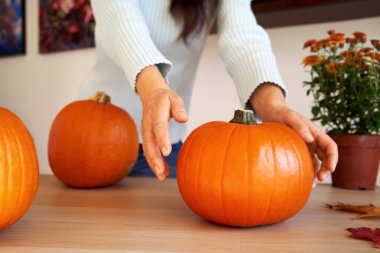 Masada bir kişinin uzandığı portakal rengi Cadılar Bayramı kabağı.
