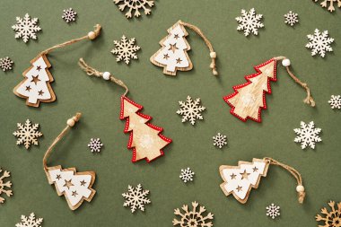 Ağaçlar ve kar taneleri şeklinde ahşap süslemeleri olan yeşil Noel arkaplanı.