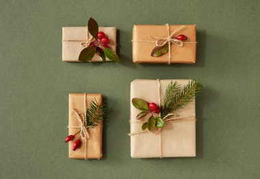 Dört Noel hediyesi ekolojik geri dönüşümlü kağıda sarılmış gül kalçası, keklik üzümü ve ladin dallarıyla