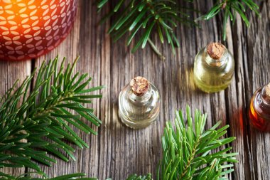 Aromaterapi şişeleri taze köknar dalları ve bir Noel mumu ile gerekli yağ