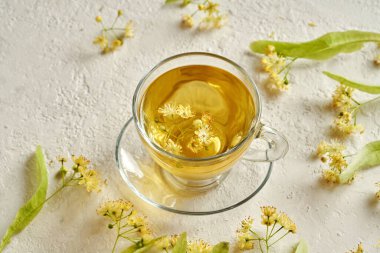 Beyaz arka planda taze ıhlamur çiçekleri olan bir fincan bitki çayı.