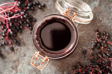 Bir kavanoz ev yapımı siyah elder şurubu ve taze mürver.