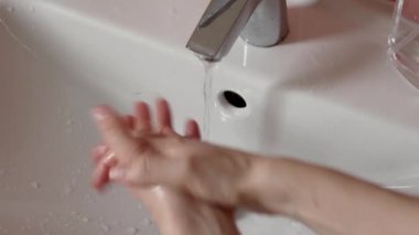 Koronavirüsten korunmak için ellerini antiviral dezenfektanla yıkamak ve musluk suyunun altında iyice yıkamak.