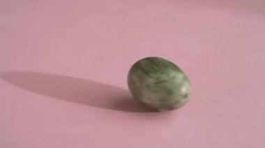 Pembe arka planda dönen yeşil yumurta, yavaş çekim