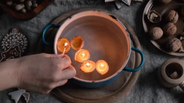 Lighting candles made from walnut shells and beeswax floating in a pot of water - old Christmas custom