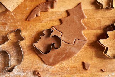 Cutting out shapes from pastry dough to prepare gingerbread Christmas cookies, top view