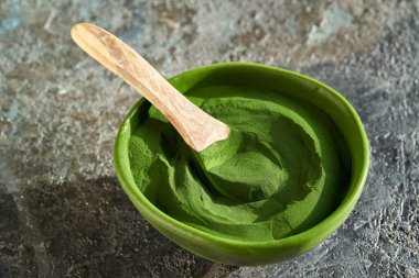 Green chlorella algae powder in a bowl on a table - healthy nutritional supplement