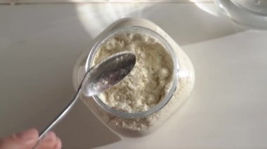 Kavanozun üstündeki kaşıkta beyaz protein tozu, yavaş çekim.