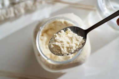 Kavanozun üstündeki kaşıkta beyaz protein tozu.
