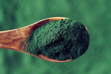 Tahta kaşıkta yeşil spirulina alg tozu, üst manzara.