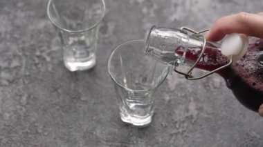 Şişeden bardağa siyah mürver şurubu döküyorum.