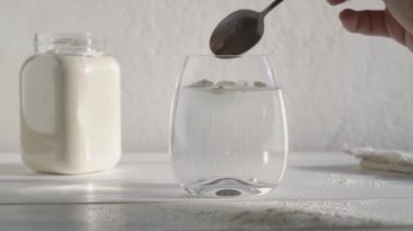 Bir bardak suya bir kaşık beyaz protein tozu koyup yavaşça karıştırmak.