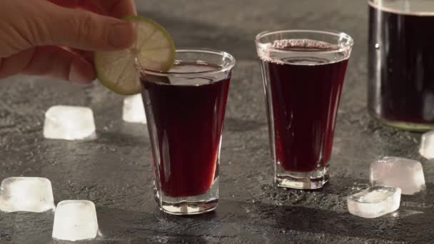 Eine Scheibe Limette Auf Ein Glas Schwarzen Holundersirup Geben — Stockvideo