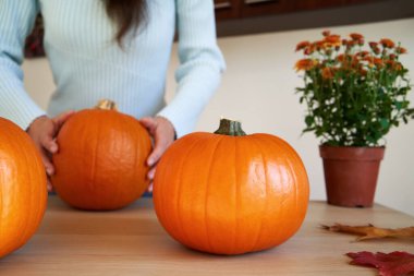 Arka planda bir kişi olan portakal rengi Cadılar Bayramı balkabağı.