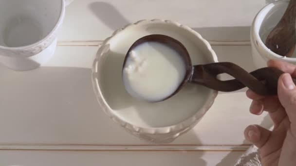 Kefir在一杯鲜牛奶之上的勺子上放着谷粒 动作缓慢 — 图库视频影像