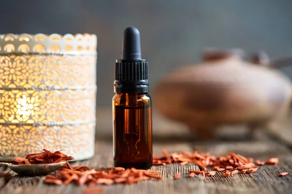 A dropper bottle of aromatherapy essential oil with red sandalwood on a table