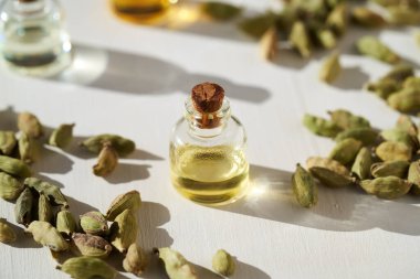 Beyaz arka planda kakule kapsülleri olan bir şişe aromaterapi.