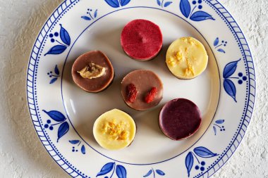 Mavi süslemeli bir tabakta yabanmersini, ahududu, limon, goji ve muz çiğ vegan Noel kurabiyesi.