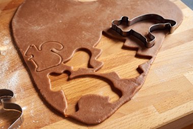 Ev yapımı zencefilli Noel kurabiyeleri hazırlamak için hamurdan çeşitli şekiller kesiyorum.