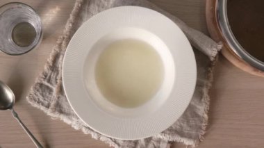 El yapımı kemik suyunu kepçeli beyaz bir tabağa döküyorum.